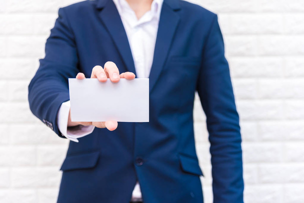 Business man showing white paper. Man  wearing blue suit and holding white blank card. Lifestyle and working concept. Business and object theme. Blank space in paper for insert text. - Photo, Image