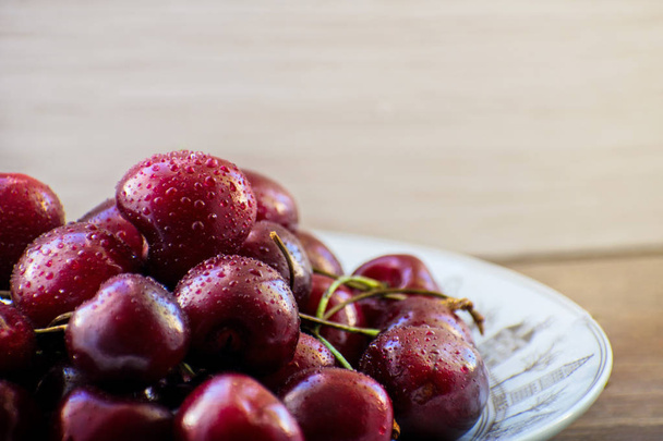 Fresh tasty cherry fruit on a plate on a wooden table - Foto, immagini