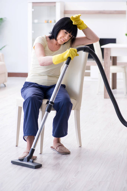 Senior old woman tired after vacuum cleaning house - Valokuva, kuva