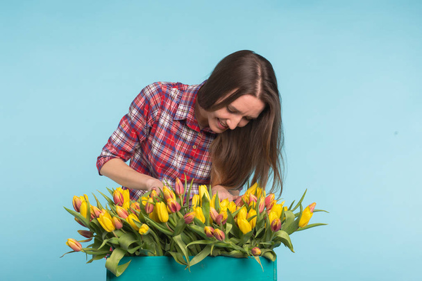 Charming female florist sorts out tulips in the box, selects them for the future flower arrangement - Photo, Image