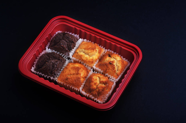 Half dozijn van heerlijke pluizig muffins in een rode doos met donkere achtergrond. - Foto, afbeelding