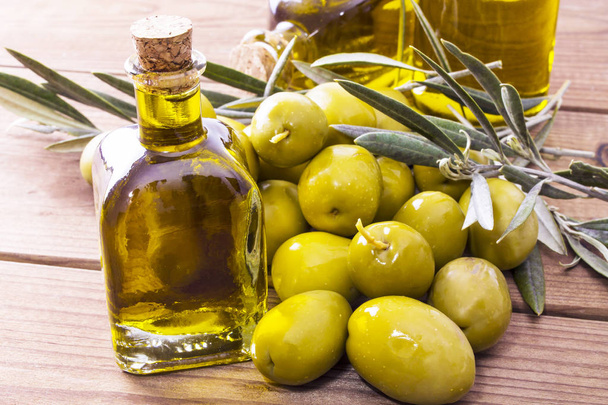 olives and bottle of extra virgin olive oil on wood - Fotografie, Obrázek