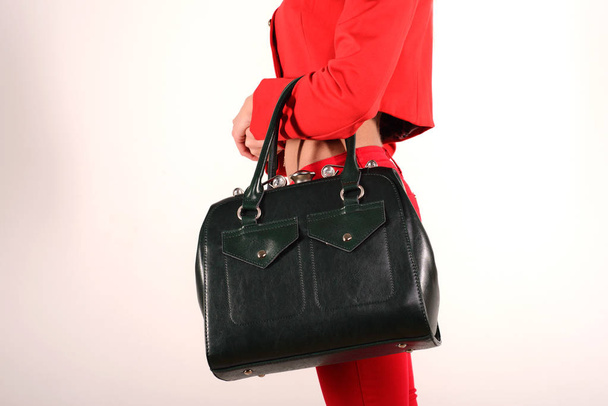 Hoikka tyttö punainen takki ja farkut vihreä laukku seisoo sivuttain
 - Valokuva, kuva