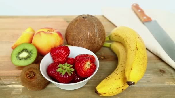 Billet for fruit cocktail on a cutting board bananas, strawberries, peach. - Video, Çekim