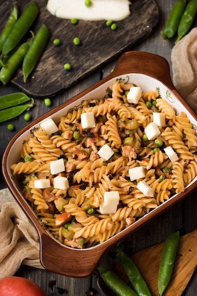 Fusilli pasta with zucchini, goat cheese and green peas on a dark rustic background - Photo, Image