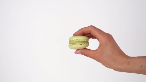 Hand holding colorful macaroons on a white background. Closeup - 映像、動画