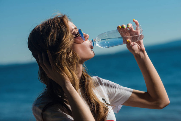 Portrait of a girl who drinks water from a bottle in summer, a woman quenches thirst - Photo, Image