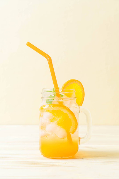 orange juice with soda on wood table - Фото, изображение