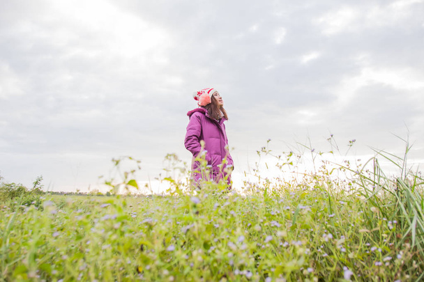 Jonge vrouw speelde op een gebied van bloemen in de winterlucht. - Foto, afbeelding