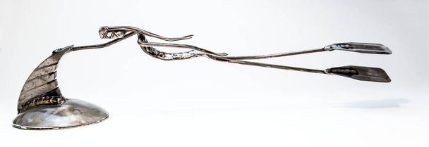 Paper holder as a figure made of welded black metal wire. Swimmer with flippers is held for a large back fin of fish, living lines. - Photo, Image