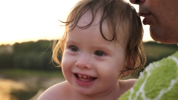 kleines Baby weint und lacht tränenüberströmt, während es in den Händen von Papa sitzt - Filmmaterial, Video