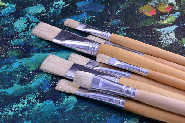 Γουρουνότριχα βούρτσες για πίνακες με χρώματα λαδιού με φόντο μια αφηρημένη ζωγραφική - Φωτογραφία, εικόνα
