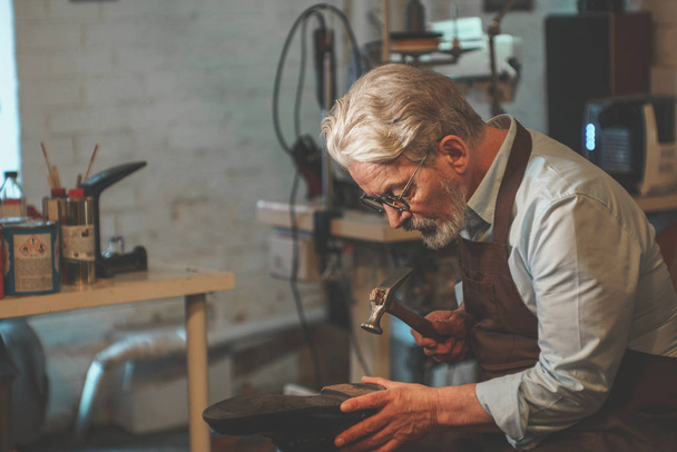 Een oudere man aan het werk in een workshop - Foto, afbeelding