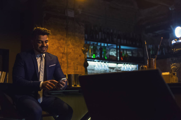 Усміхнений бізнесмен використовує смартфон у барі
 - Фото, зображення