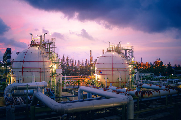 Резервуары для хранения газа в нефте- и газоперерабатывающей промышленности с трубопроводом, закат неба с нефтехимическим заводом, блестящее освещение нефтеперерабатывающего завода на заре неба
 - Фото, изображение