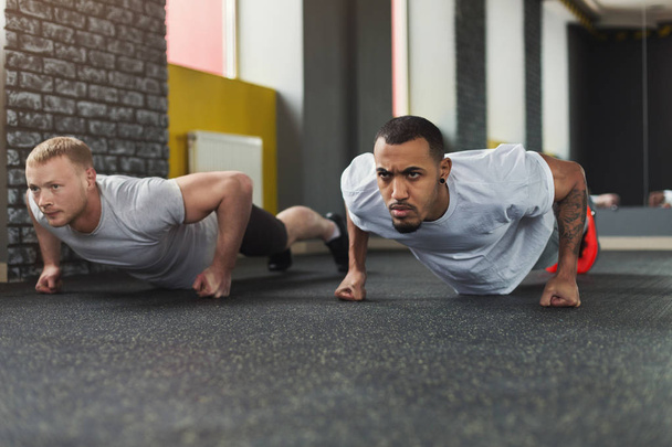 Two happy men fitness workout together at gym - Photo, Image