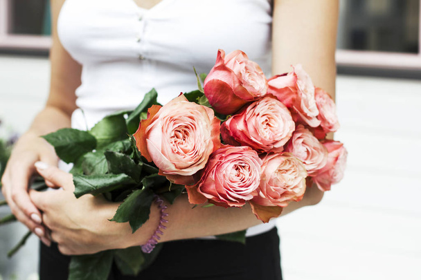 Young woman florist holding bouquet of pink roses at the street - 写真・画像