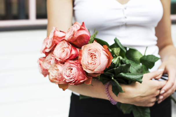 Nuori nainen kukkakauppa tilalla kimppu vaaleanpunainen ruusuja kadulla
 - Valokuva, kuva