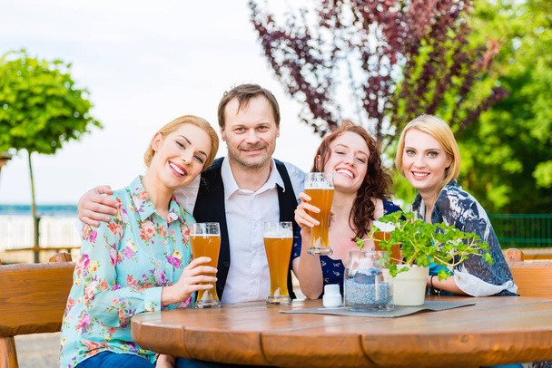 Friends toasting with beer in garden restaurant - Photo, Image