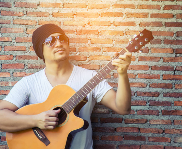 Νέοι hipster άντρας παίζει κιθάρα να χαλαρώνετε στις διακοπές του, Απολαύστε με φυσικό και φρέσκο αέρα. - Φωτογραφία, εικόνα