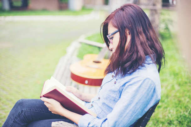 Хіпстер чарівна дівчина розслабляється в парку під час читання книги, Насолоджуйтесь природою навколо
. - Фото, зображення
