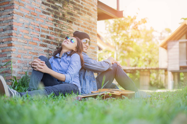 Hipster homem tocando guitarra para sua namorada ao ar livre contra a parede de tijolo, desfrutando juntos
. - Foto, Imagem