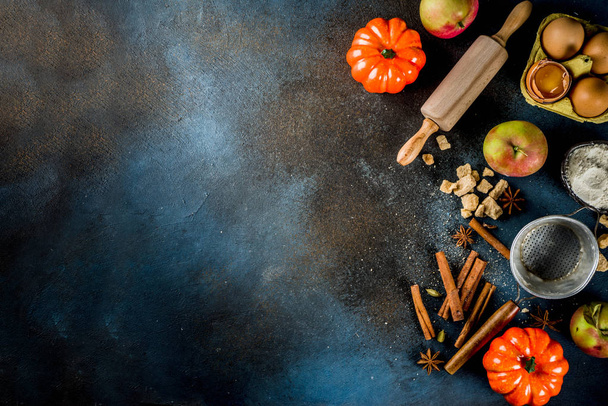 Sweet autumn baking cooking background with flour, rolling pin, decorative pumpkins, apples, cinnamon spices with anise cardamom sugar. Dark blue rusty background top view copy space - Photo, Image