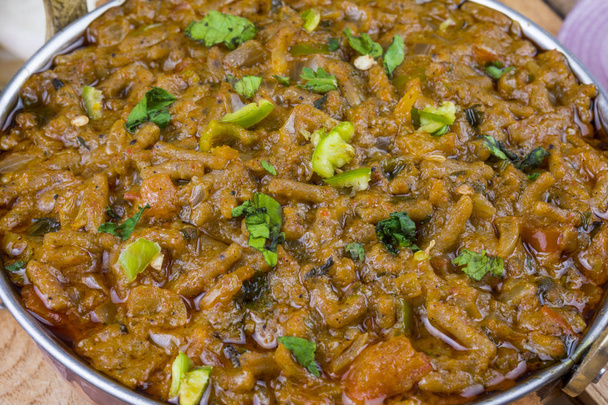 Die indische Küche sev tamatar, auch sev tamaeta oder sev tameta genannt, wird mit Chapati, Papade, Zwiebeln oder Raita serviert. Es wird mit Tomaten-Zwiebeln-Sauce mit einem Hauch von würzigem sev auf dem Holztisch zubereitet - Foto, Bild