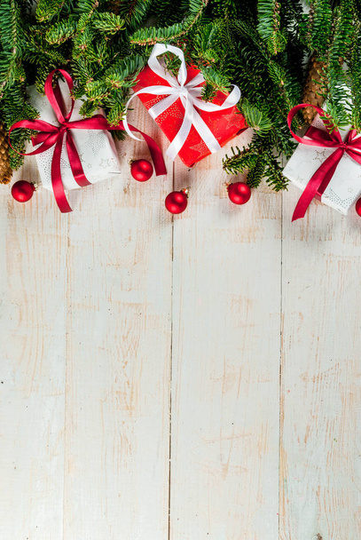 Joulun uudenvuoden tausta, onnittelukortin konsepti, valkoinen puinen tausta joulukuusen oksilla, juhlapalloilla, lahjapakkauksilla ja käpyillä kopioi tilaa ylhäältä
 - Valokuva, kuva