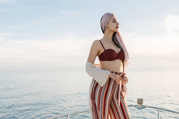 luottavainen seksikäs tyttö tyylikkäissä kesävaatteissa nauttii merimatkasta jahdilla
 - Valokuva, kuva