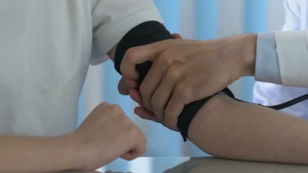 Doctor measuring boy blood pressure with stethoscope, draft checkup medical care - Felvétel, videó