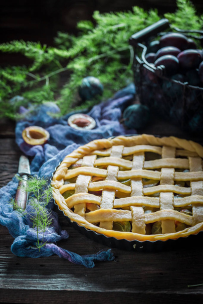 Closeup of homemade tart with plums on blue cloth - 写真・画像