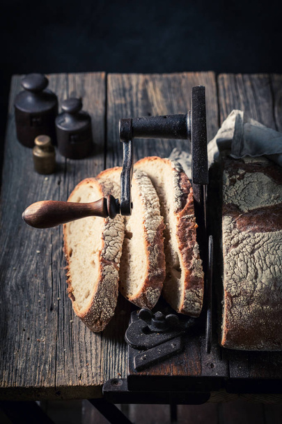 Homemade tasty loaf of bread on old slicer - Фото, зображення