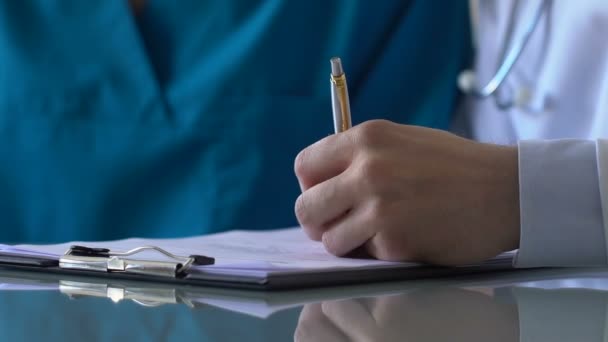 Doctor and nurse filling report document, medical intern practicing in hospital - Filmagem, Vídeo