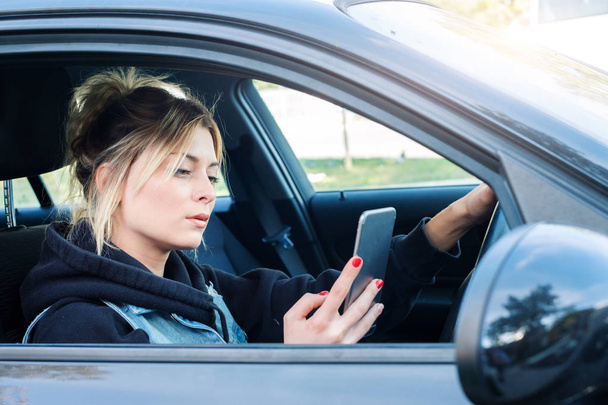 Γυναίκα οδήγηση αυτοκινήτου αποσπούν την προσοχή από το κινητό της τηλέφωνο - Φωτογραφία, εικόνα