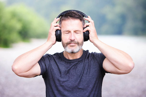 portrait of handsome bearded man with headphones outdoors - Photo, Image
