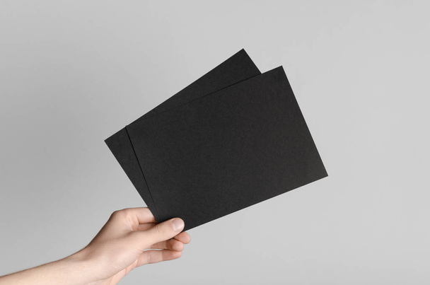 Black A5 Flyer / Invitation Mock-Up - Male hands holding black flyers on a gray background. - Fotoğraf, Görsel