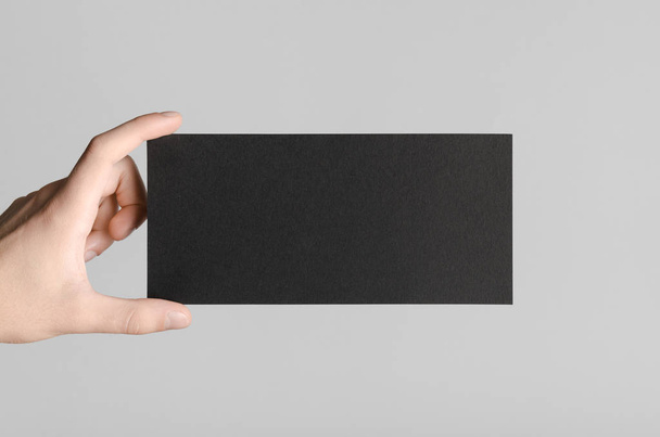 Black DL Flyer Mock-Up - Male hands holding a black flyer on a gray background. - Photo, image