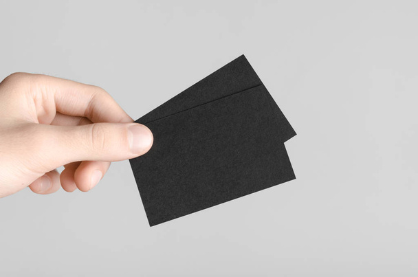 Black Business Card Mock-Up (85x55mm) - Male hands holding blank cards on a gray background. - Foto, afbeelding