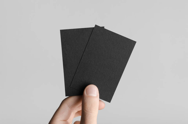 Black Business Card Mock-Up (85x55mm) - Male hands holding blank cards on a gray background. - Fotó, kép