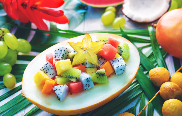 Exotic tropical fruits salad served in half a melon on leaves of palm trees - Photo, Image