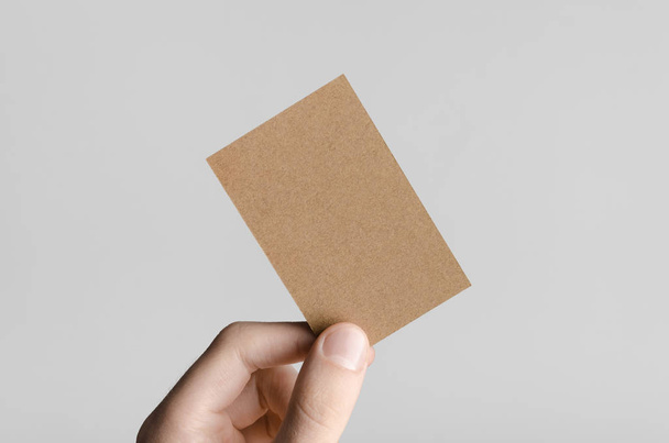 Kraft Business Card Mock-Up (85x55mm) - Male hands holding a kraft card on a gray background. - Foto, Bild