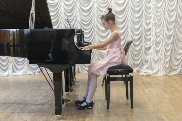 üzerinde siyah bir grand piyano güzel pembe elbiseli kız. Üzerinde siyah bir piyano çalan kız - Fotoğraf, Görsel