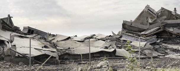 Edificio de hormigón industrial destruido por la huelga. Escena desastrosa llena de escombros, polvo y edificios estrellados
. - Foto, imagen