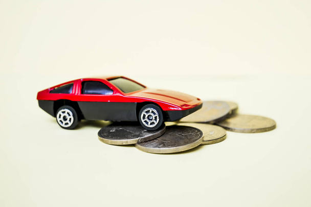 Red toy car rides up a stack of coins - Фото, изображение