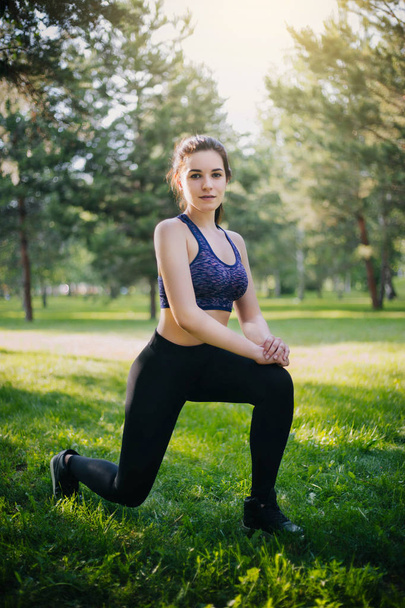 Una hermosa chica en el parque se dedica a los deportes. Un modelo con piel limpia y oboyatelnoy ulvbkoy en ropa deportiva. Entrenamientos al aire libre
. - Foto, imagen