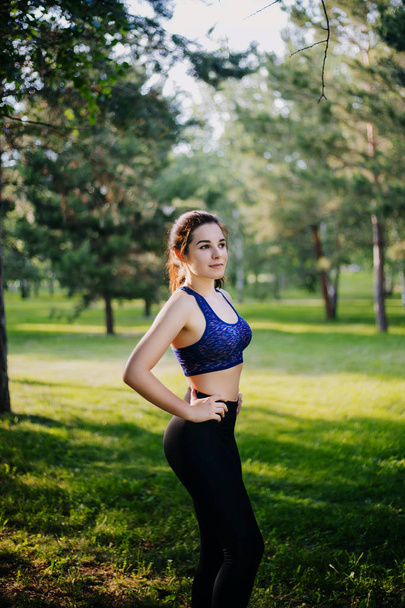 A beautiful girl in the park is engaged in sports. A model with clean skin and oboyatelnoy ulvbkoy in sportswear. Open-air trainings. - 写真・画像
