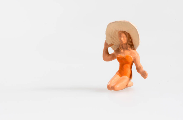 Miniatura de mujer arrodillada usando sombrero de playa mientras toma el sol
 - Foto, imagen