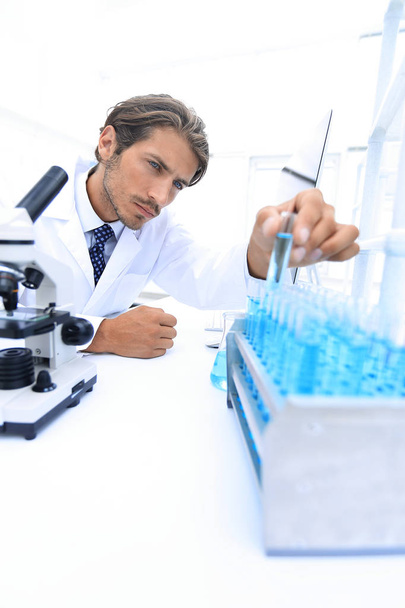 Chemist looking at test-tubes with blue liquids - Fotó, kép