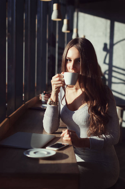 Beautiful cute girl in cafe drinks coffee - Fotoğraf, Görsel
